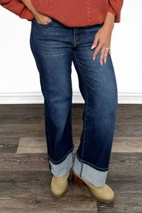 Person wearing blue jeans and a red sweater on a wooden floor.