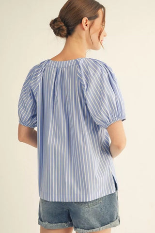 Woman wearing a blue and white striped shirt with rolled-up sleeves on a beige background