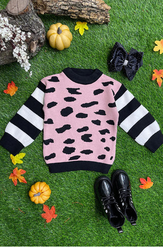 Pink sweater with black leopard print and striped sleeves on a grassy background with pumpkins and leaves.
