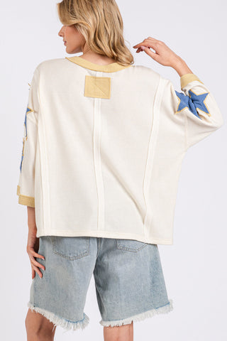 Woman wearing a cream-colored top with star and moon designs on a white background