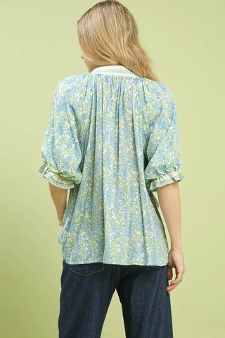 Woman wearing a light blue floral blouse against a green background