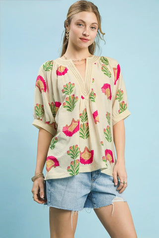 Woman wearing a floral blouse and denim shorts against a light blue background