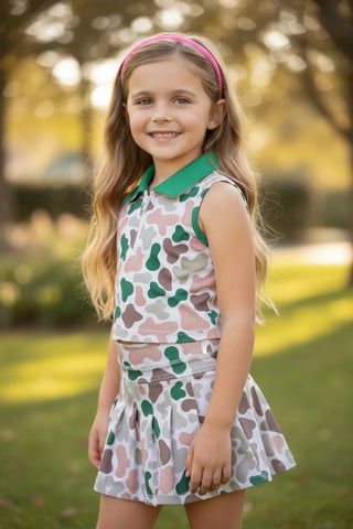 Young girl in a patterned dress standing outdoors with trees in the background