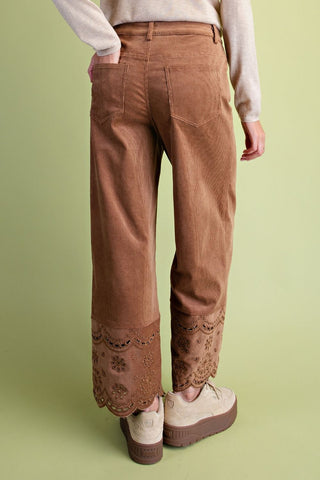 Brown corduroy pants with lace trim worn by a person on a green background