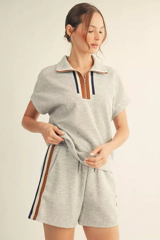 Woman wearing a gray romper with a zipper detail on a beige background