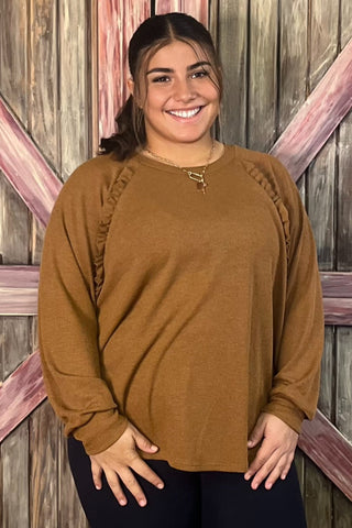 Person wearing a brown sweater standing in front of a wooden door