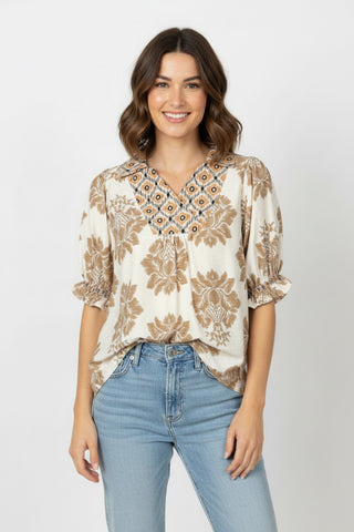 Woman wearing a patterned blouse and jeans on a white background