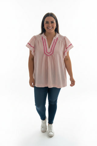 Striped shirt with ruffled trim held up in front of a store window.