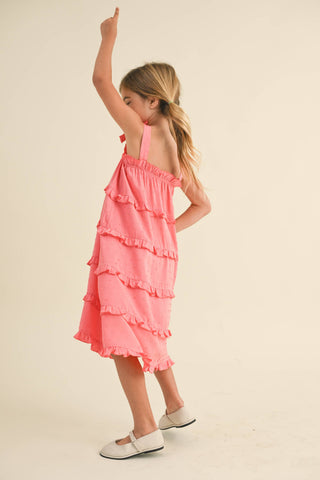 Young girl wearing a pink ruffled dress on a beige background