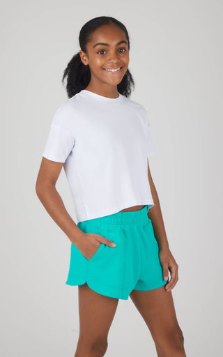 Person wearing a white t-shirt and teal shorts on a plain background