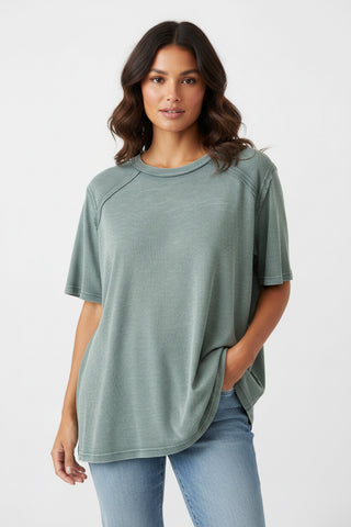 Woman wearing a green t-shirt and blue jeans on a white background