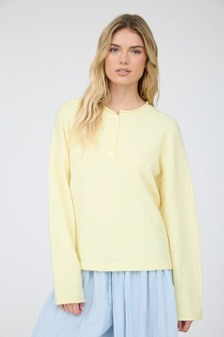 Woman wearing a light yellow sweater and light blue skirt against a white background