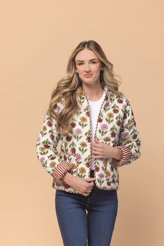 woman wearing floral print jacket in front of a taupe background