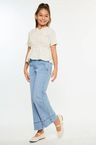 Young girl wearing a white blouse and light blue jeans on a white background