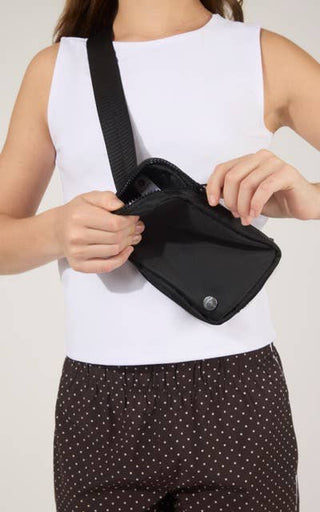 Person holding a black waist bag against a plain background