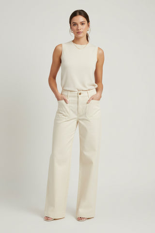 Woman wearing a cream sleeveless top and wide-leg pants on a white background