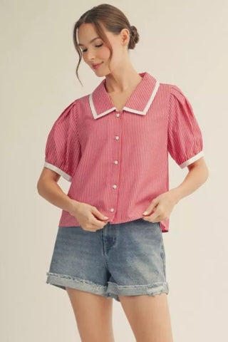 Woman wearing a red and white checkered blouse with a collar and blue shorts on a beige background