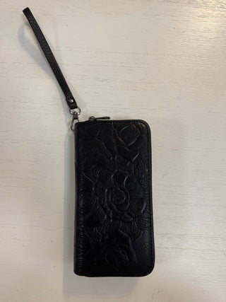 Black embossed wallet with wrist strap on a light wooden surface