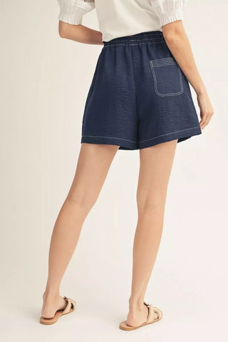 Person wearing navy shorts on a plain background