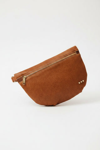 Brown leather bag held by a person wearing a denim jacket.
