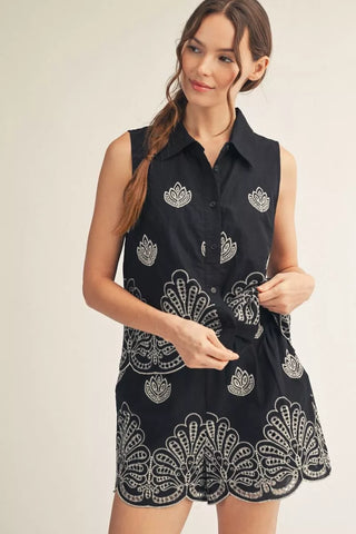 Woman wearing a black sleeveless dress with white patterns on a beige background