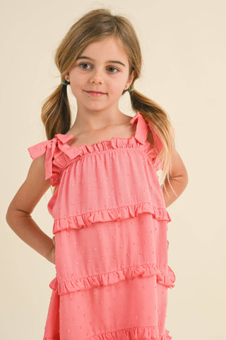 Young girl wearing a pink dress with ruffles on a beige background