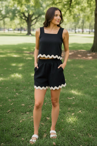 Woman in a black outfit with white trim standing in a park