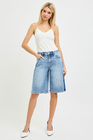 Woman wearing a white tank top and blue denim shorts on a white background