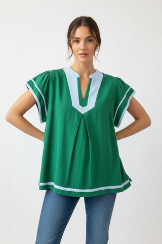 Woman wearing a green blouse with white trim on a white background