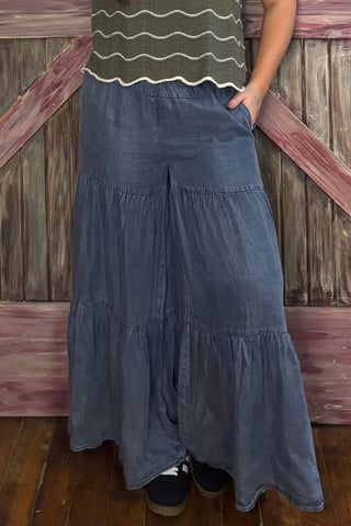 Person wearing a long denim pants and green top against a wooden background