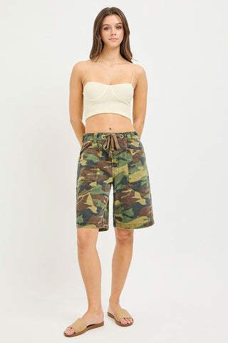 Woman wearing camouflage shorts on a white background