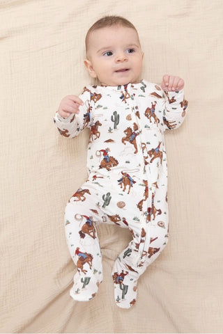 Baby wearing a onesie with cowboy print on a beige blanket