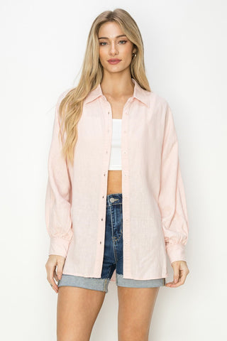 Woman wearing a light pink shirt over a white top and blue shorts on a white background