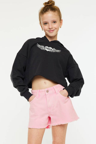 Child wearing a black hoodie with a logo and pink shorts on a white background