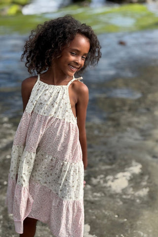 Young girl in a floral dress standing by a body of water