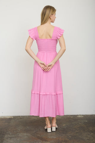 Woman wearing a pink dress with ruffled sleeves against a white background