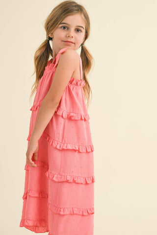 Young girl wearing a pink dress with ruffled layers on a beige background