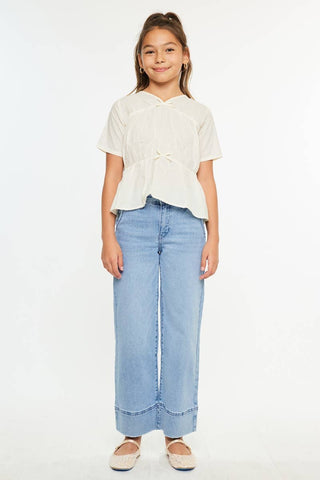 Young girl wearing a white top and light blue jeans on a white background