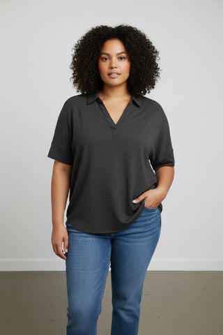 Woman wearing a black shirt and blue jeans against a plain background