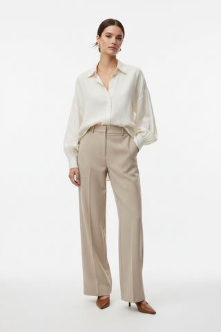 Woman wearing a white blouse and beige pants on a white background