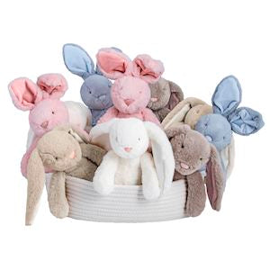 Basket of soft toy bunnies in various colors on a white background