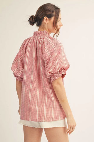Woman wearing a red and white checkered blouse on a plain background