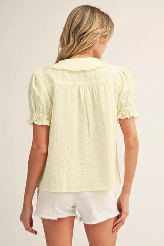 Woman wearing a light yellow blouse and white shorts on a plain background