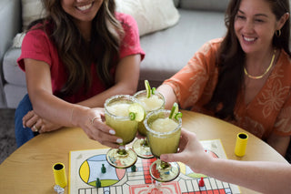 Two women enjoying drinks together at a table with a board game.