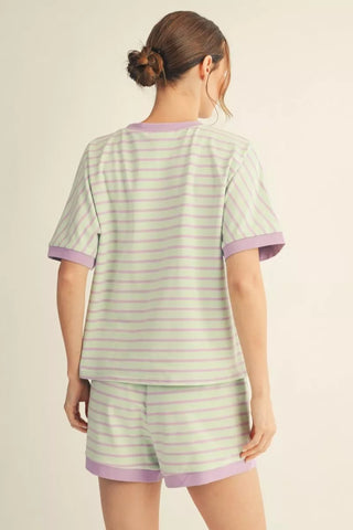Person wearing a green and purple striped pajama set on a beige background