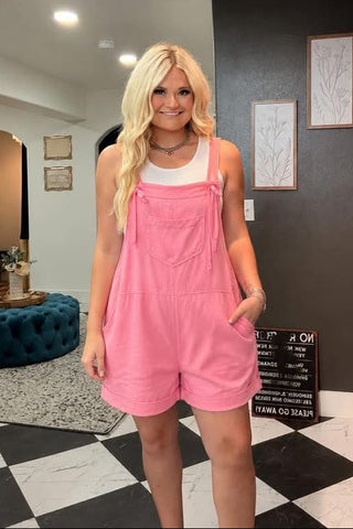 Woman wearing pink overalls in a room with checkered floor and shelves.