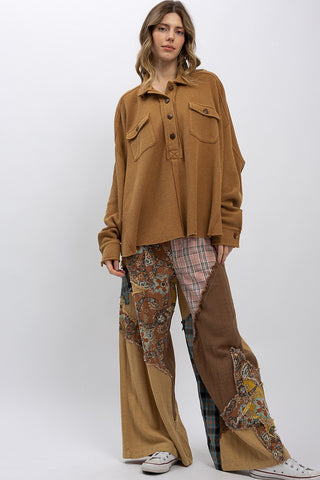 Person wearing a brown jacket and patchwork pants on a white background