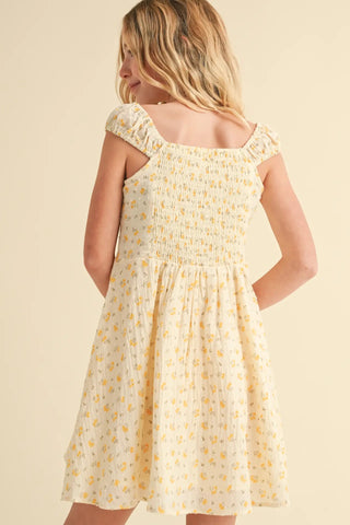Young girl wearing a yellow floral dress against a beige background