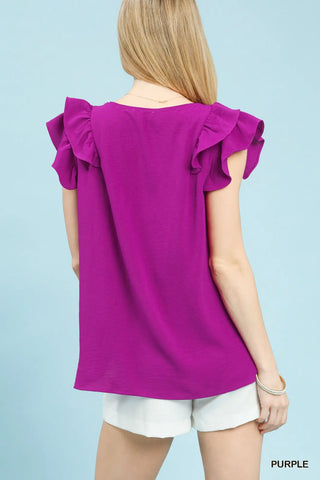 Woman wearing a purple blouse with ruffled sleeves on a light blue background