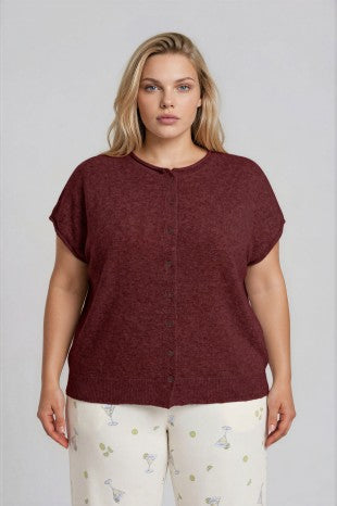 Woman wearing a brown button-up shirt and light-colored pants with a subtle pattern.